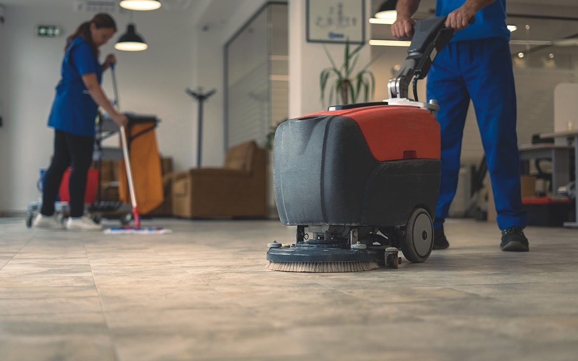 Reinigungskraft mit Scheuersaugmaschine in einem modernen Bürogebäude